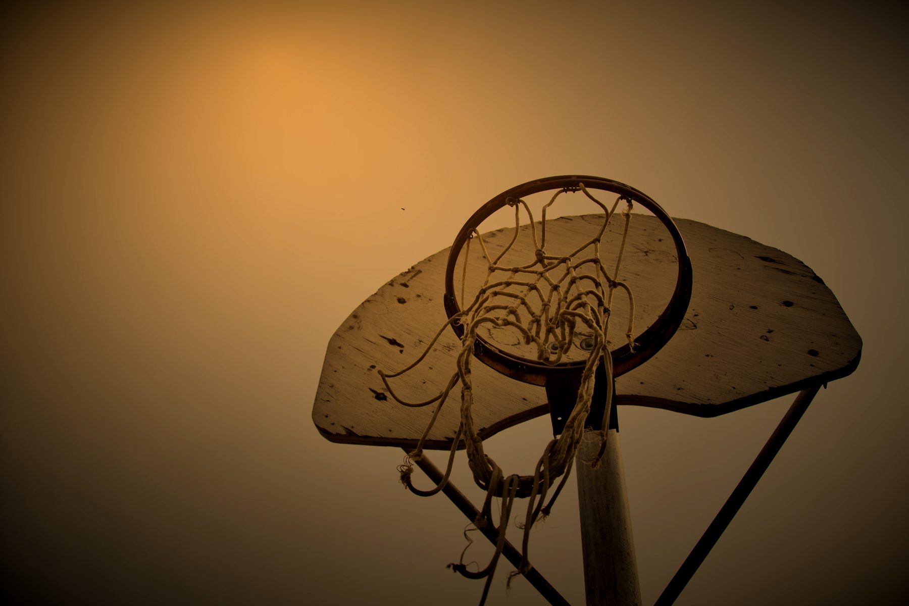 Bare outdoor hoop and backboard on an overcast evening